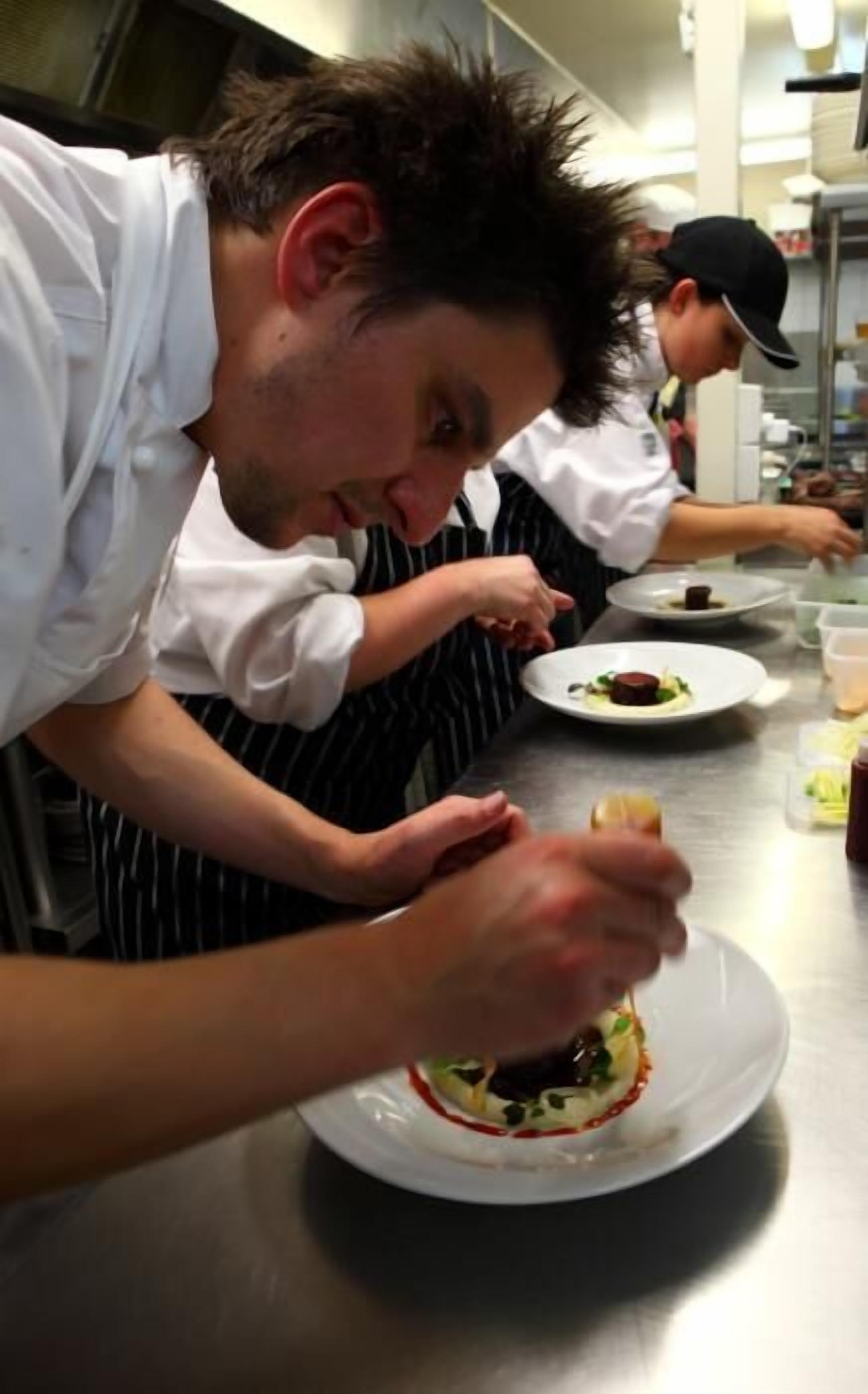 Chefs preparing dishes in a professional kitchen.