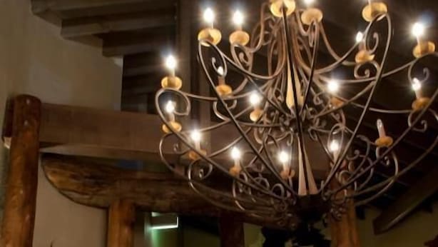 A chandelier with multiple light bulbs hanging from a metal frame. - Hotel High Plains (Dinner Plain)