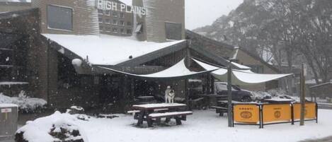 Ein Gebäude namens 'HIGH PLAINS' mit Außenbestuhlung und Schnee.