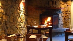 A restaurant with stone walls and a fireplace. Tables are set with wine glasses and plates. - Hotel High Plains (Dinner Plain)