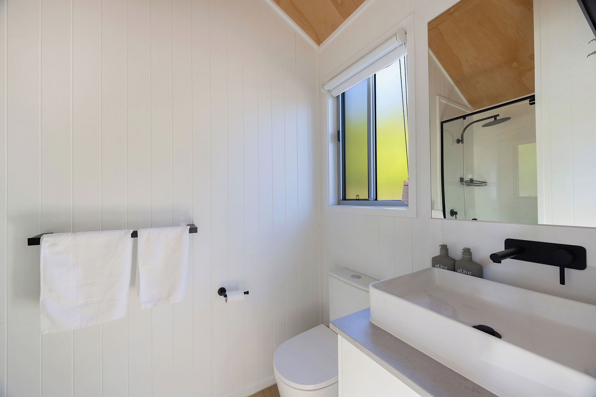 Un baño moderno con tocador blanco, inodoro y ducha.