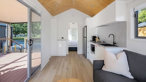 A compact, modern kitchen with a wooden ceiling, a built-in oven, and a sink. - Reflections Tumut River (Tumut)