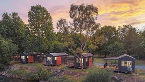A row of small cabins by a river, each with a deck and a view of the water. - Reflections Tumut River (Tumut)