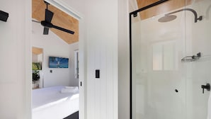 A modern bedroom with a bed, a ceiling fan, and a glass shower enclosure. - Reflections Tumut River (Tumut)