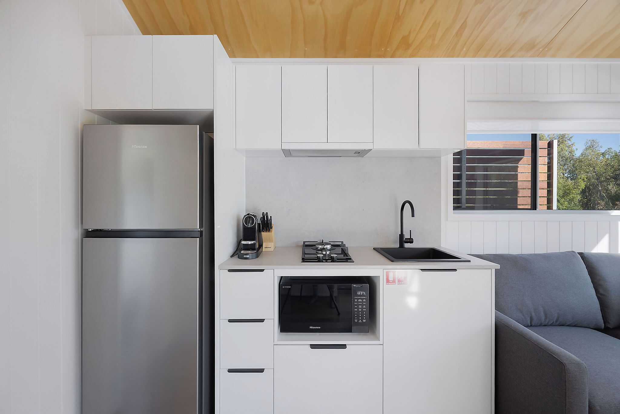 A compact kitchen with a built-in microwave, a gas stove, and a stainless steel refrigerator.