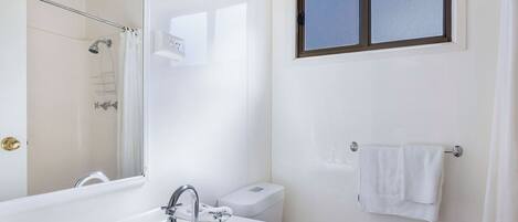 A bathroom with a bathtub, a toilet, a window, and a towel rack.