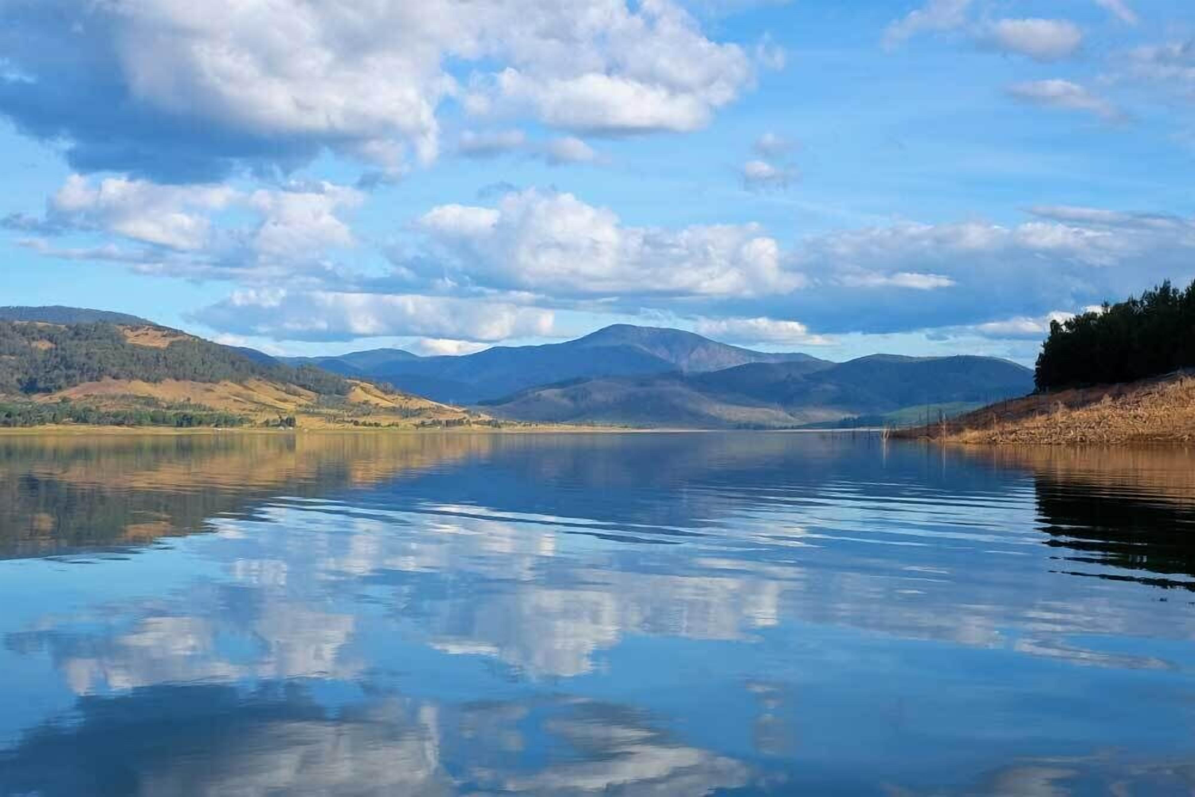 Un lac paisible, avec des montagnes en arrière-plan et un ciel dégagé.