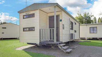 A mobile home with a porch, a small deck, and a fenced yard.