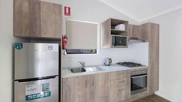 Una cocina moderna con armarios de madera, un refrigerador de acero inoxidable, un microondas, una estufa a gas y un lavamanos.