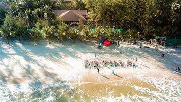 Na praia, areia branca, espreguiçadeiras, guarda-sóis