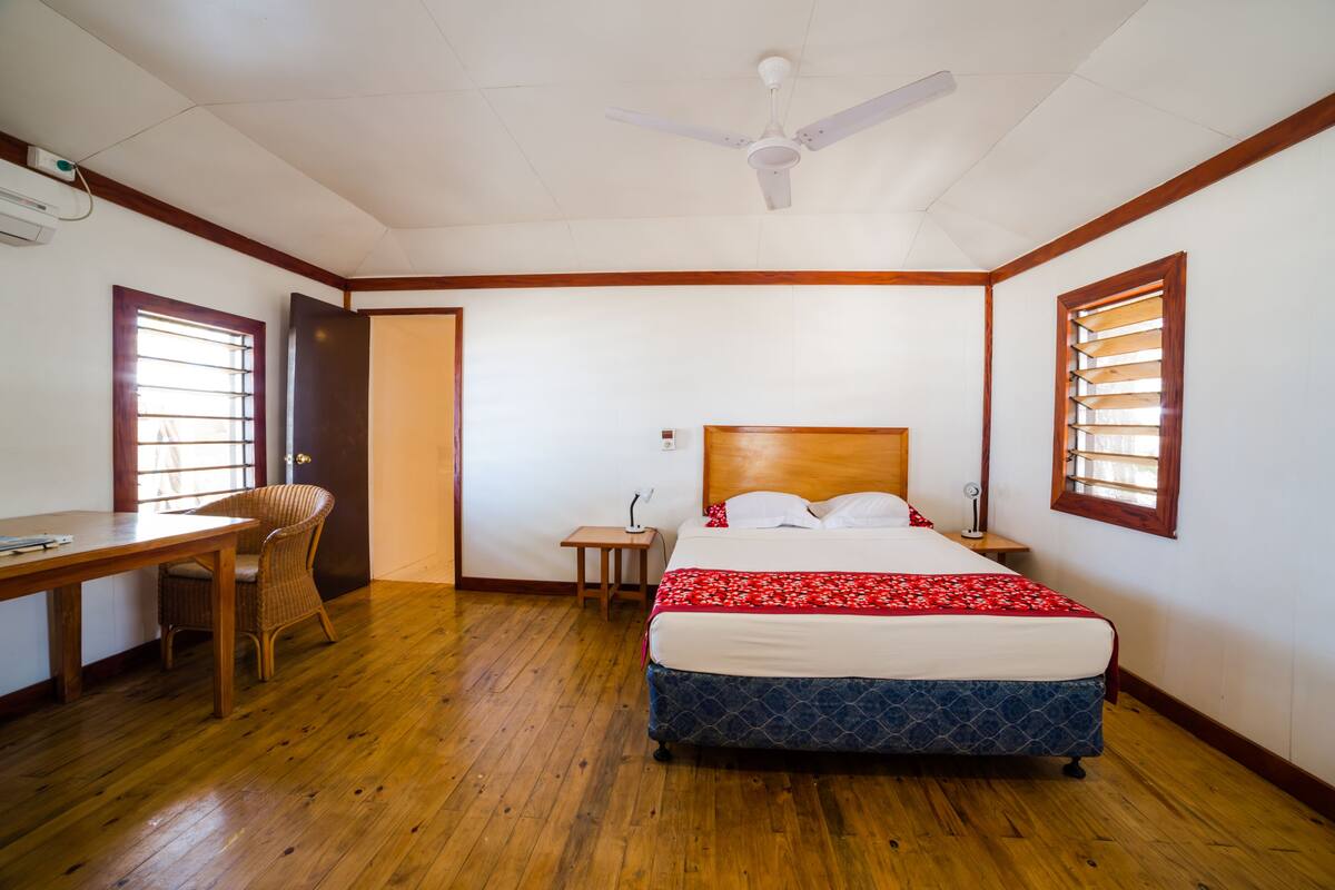 A bedroom with a wooden bed, a desk, and a chair.