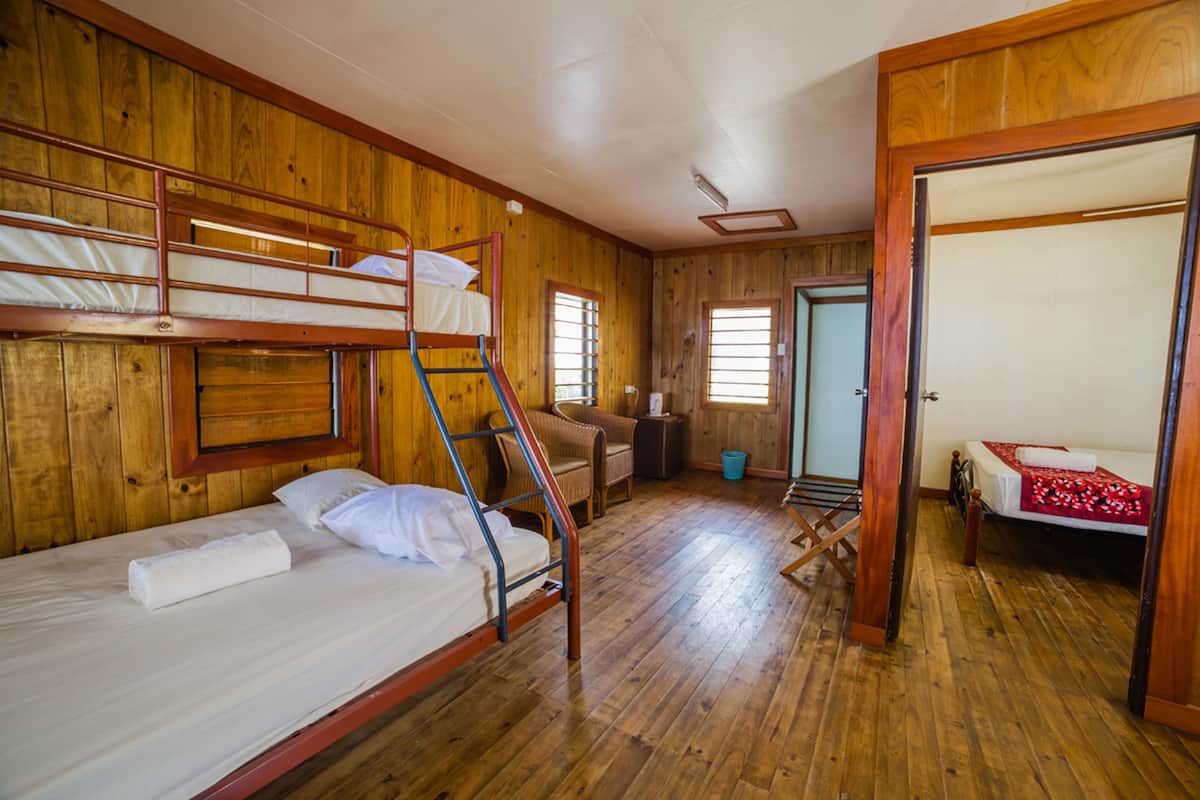A wooden cabin with bunk beds, a chair, and a small table.