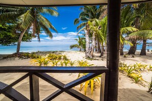 A beach view with palm trees and a wooden deck. - Ratu Kini Backpackers & Dive Resort (Mana Island)