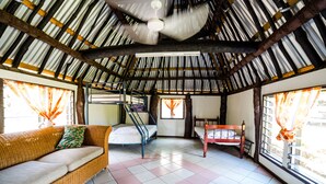 A room with a high ceiling, a bed, a sofa, and a window with curtains. - Ratu Kini Backpackers & Dive Resort (Mana Island)