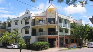 A multi-story building with a central atrium, balconies, and storefronts including a food market. - Magnetic Sunsets Resort (Horseshoe Bay)