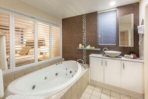 Ein modernes Badezimmer mit einer großen Badewanne, einem Waschtisch mit Waschbecken und einem Spiegel darüber.