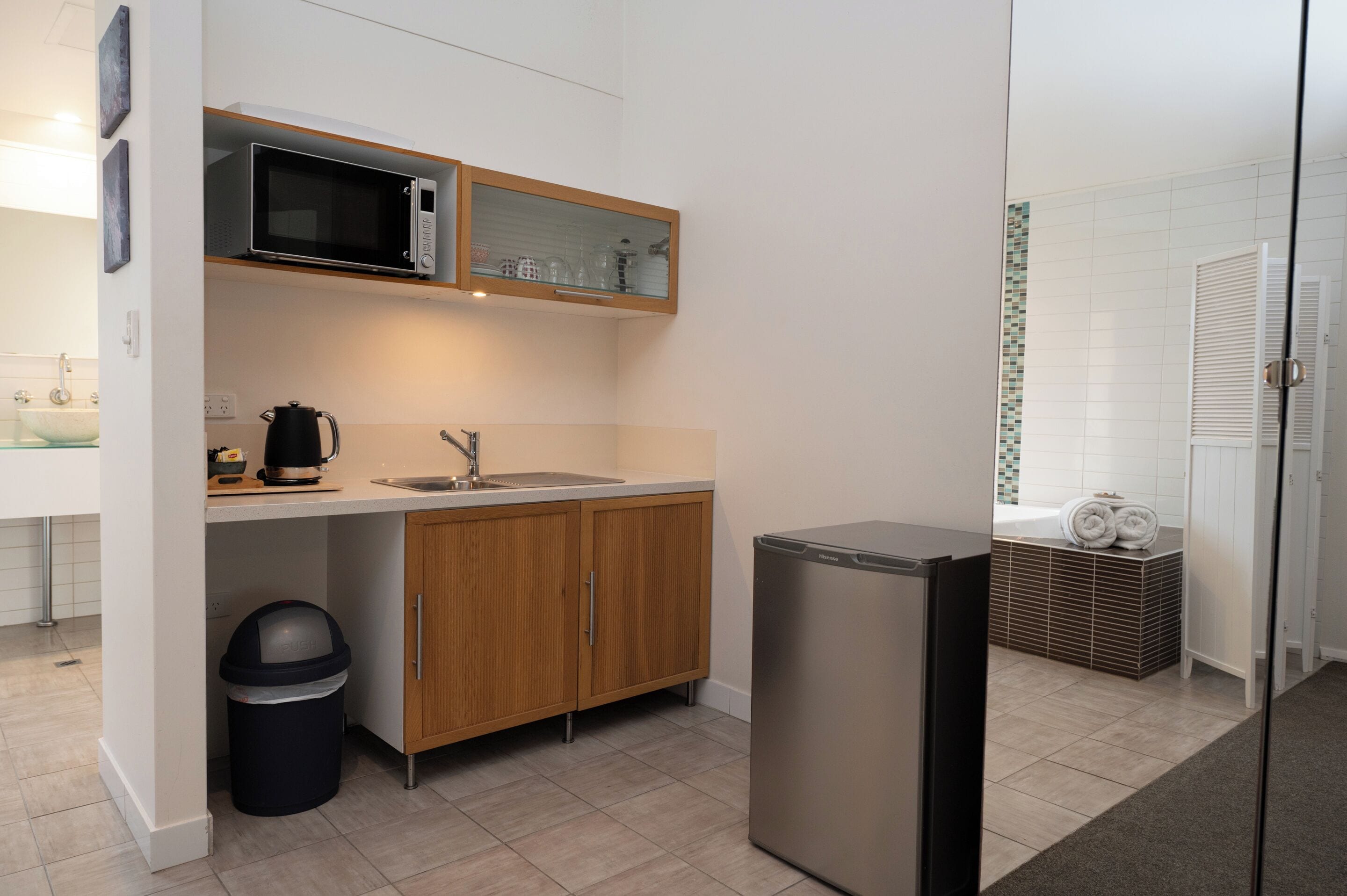 A compact kitchen with a microwave, sink, and a small refrigerator.