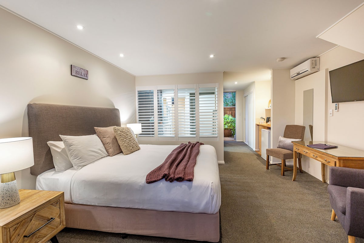 Habitación de hotel con una cama grande, un escritorio, una silla y un televisor.