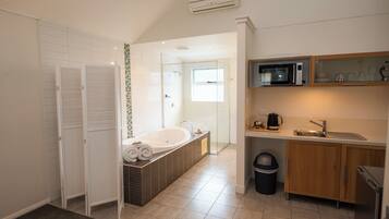 Een moderne badkamer met een vrijstaand bad, een douchegedeelte en een keuken met een magnetron en spoelbak.