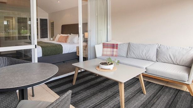Habitación de hotel moderna con balcón, sofá, una mesita y cama con vistas a la ciudad.