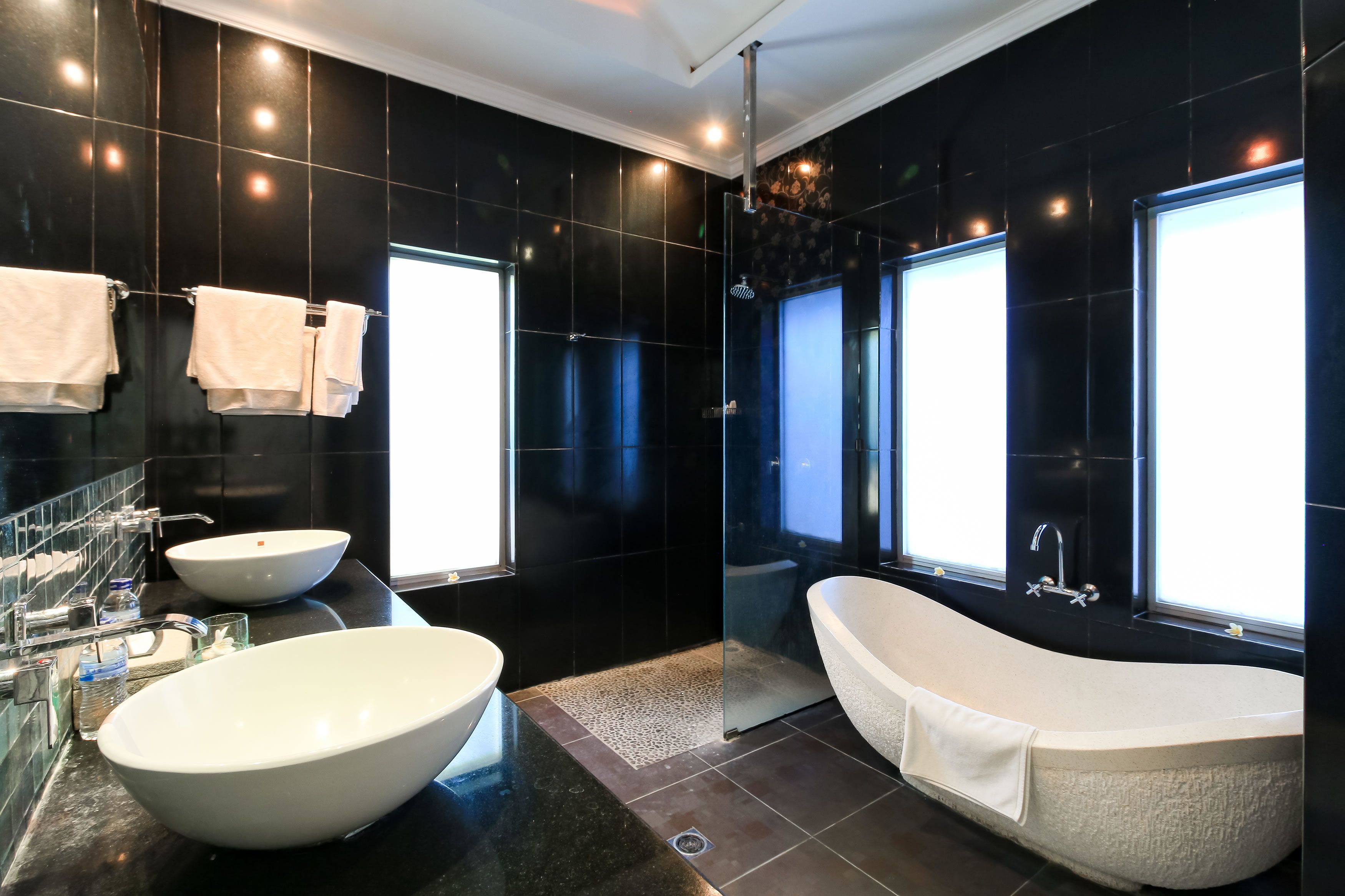 A modern bathroom with a large freestanding bathtub, a freestanding sink, and a glass-enclosed shower.