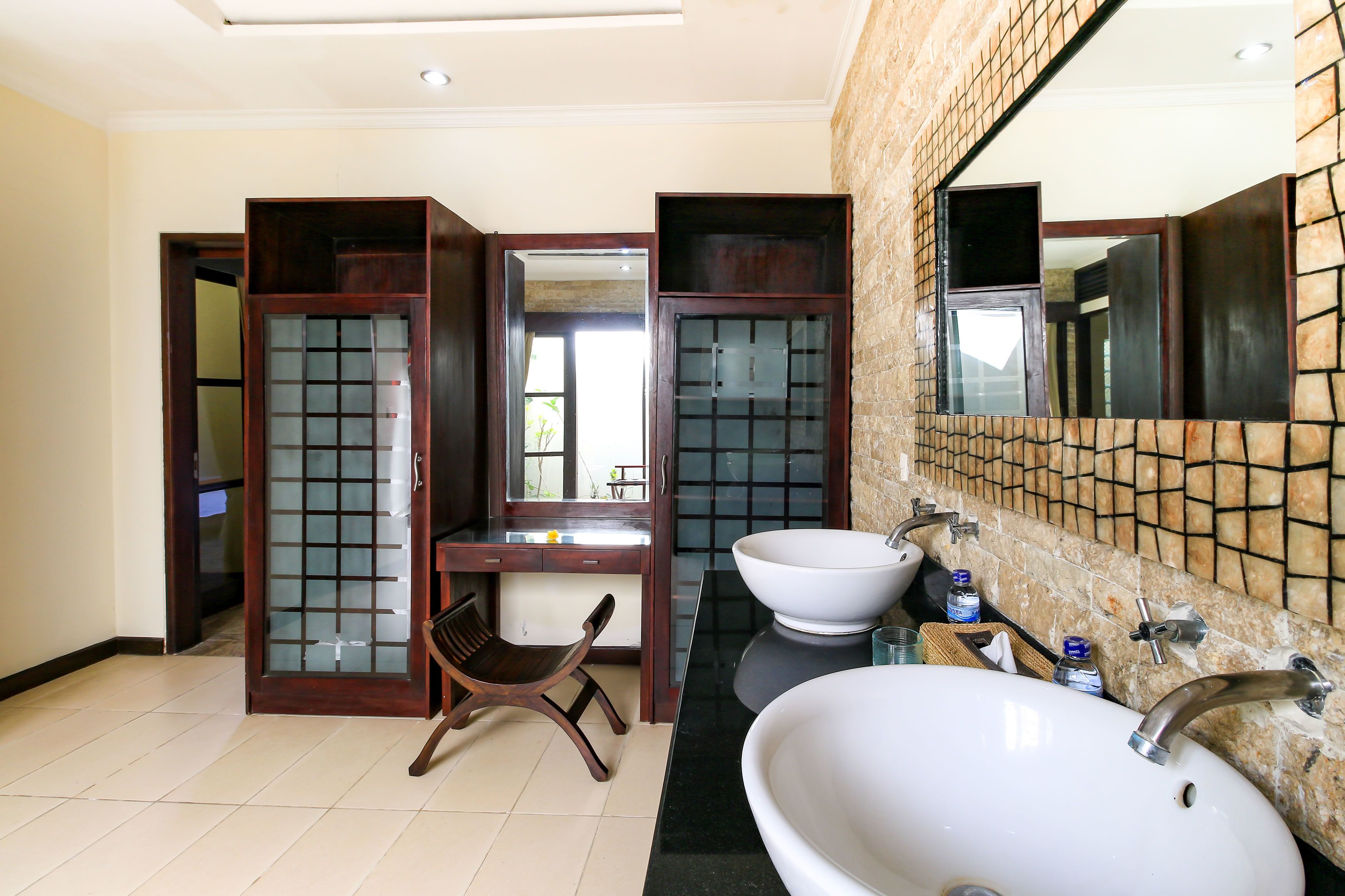 A bathroom with a wooden chair, two sinks, and a large mirror.