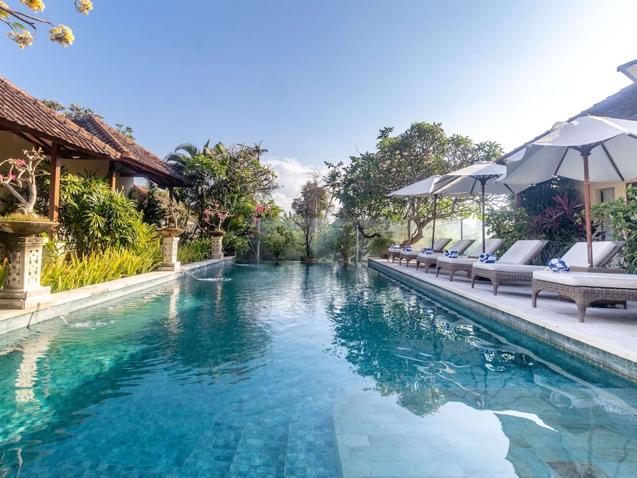Una piscina al aire libre, sombrillas, sillones reclinables de piscina