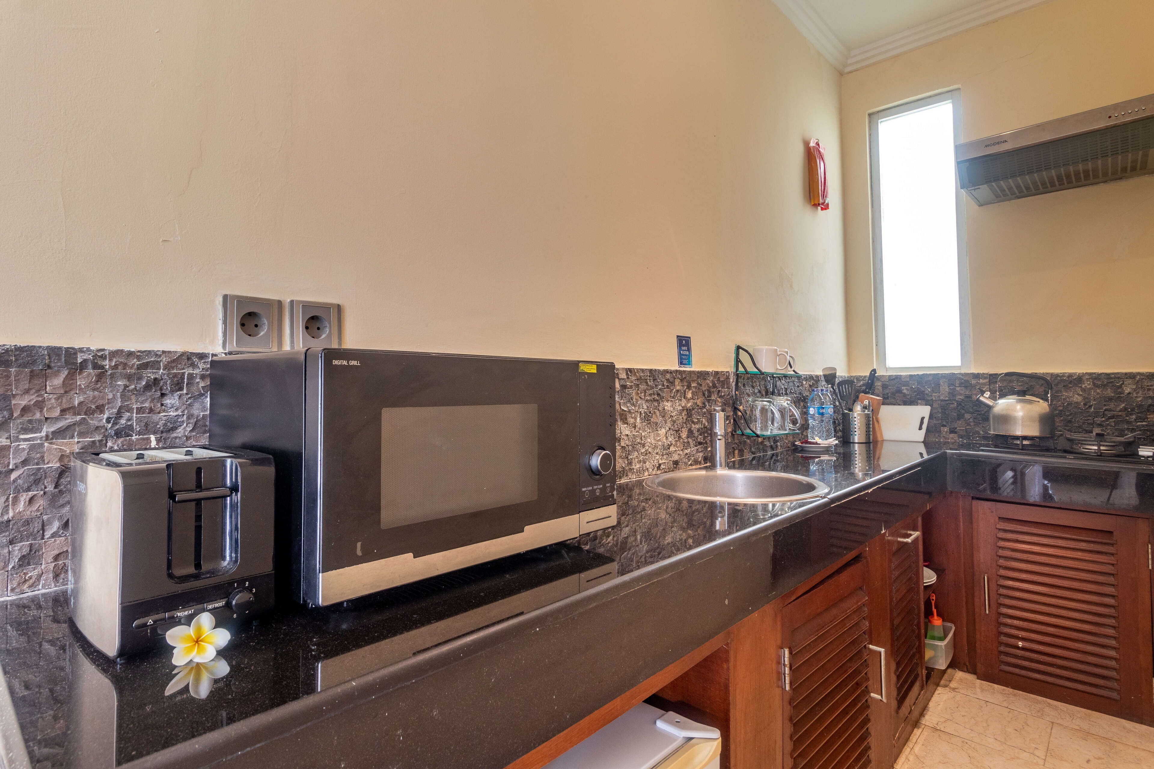 A kitchen with a toaster, microwave, sink, and granite countertop.