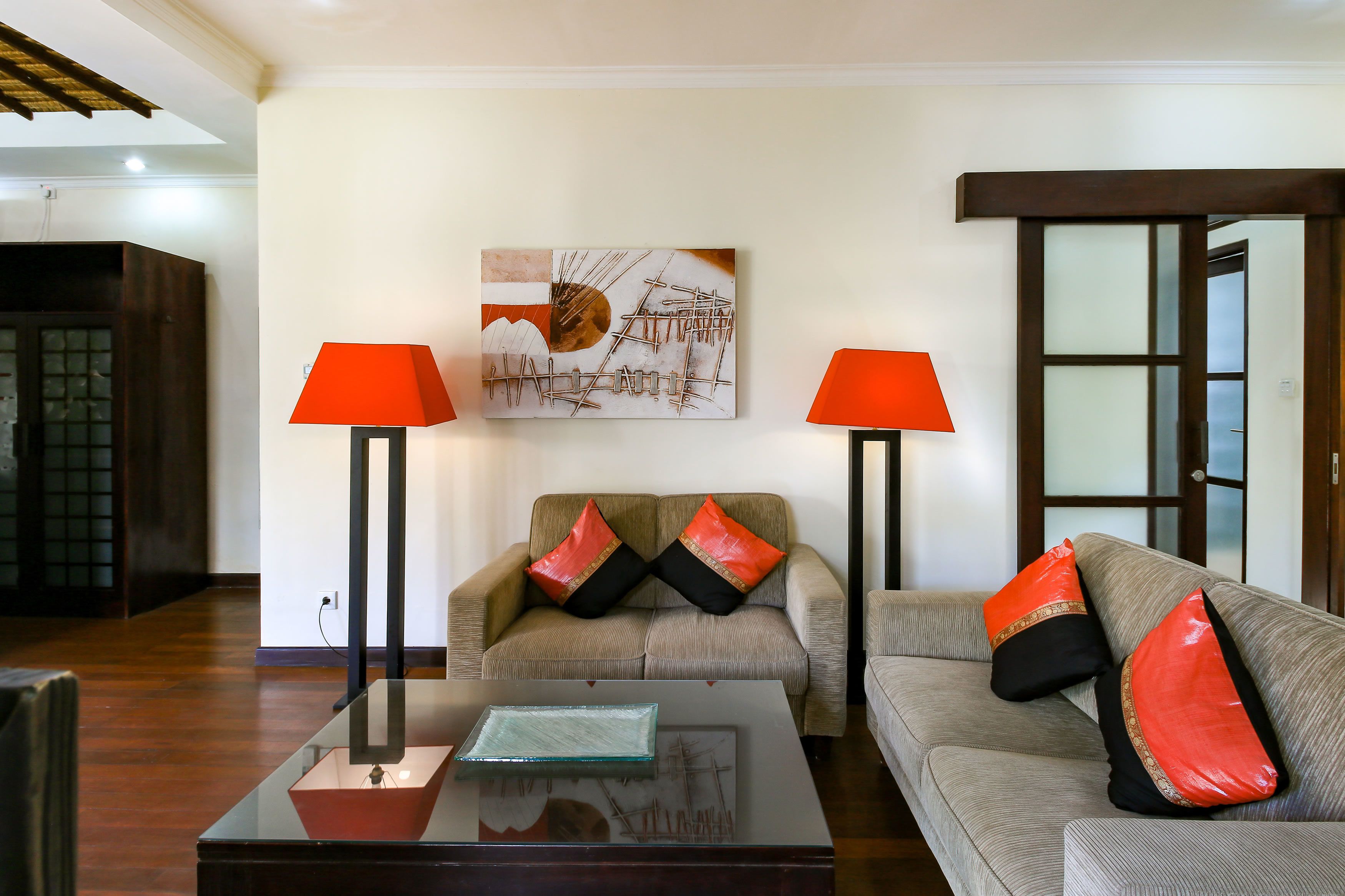 A living room with a sofa, two armchairs, a coffee table, and two floor lamps.
