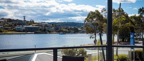 A view from a balcony overlooking a body of water with buildings and trees in the background.