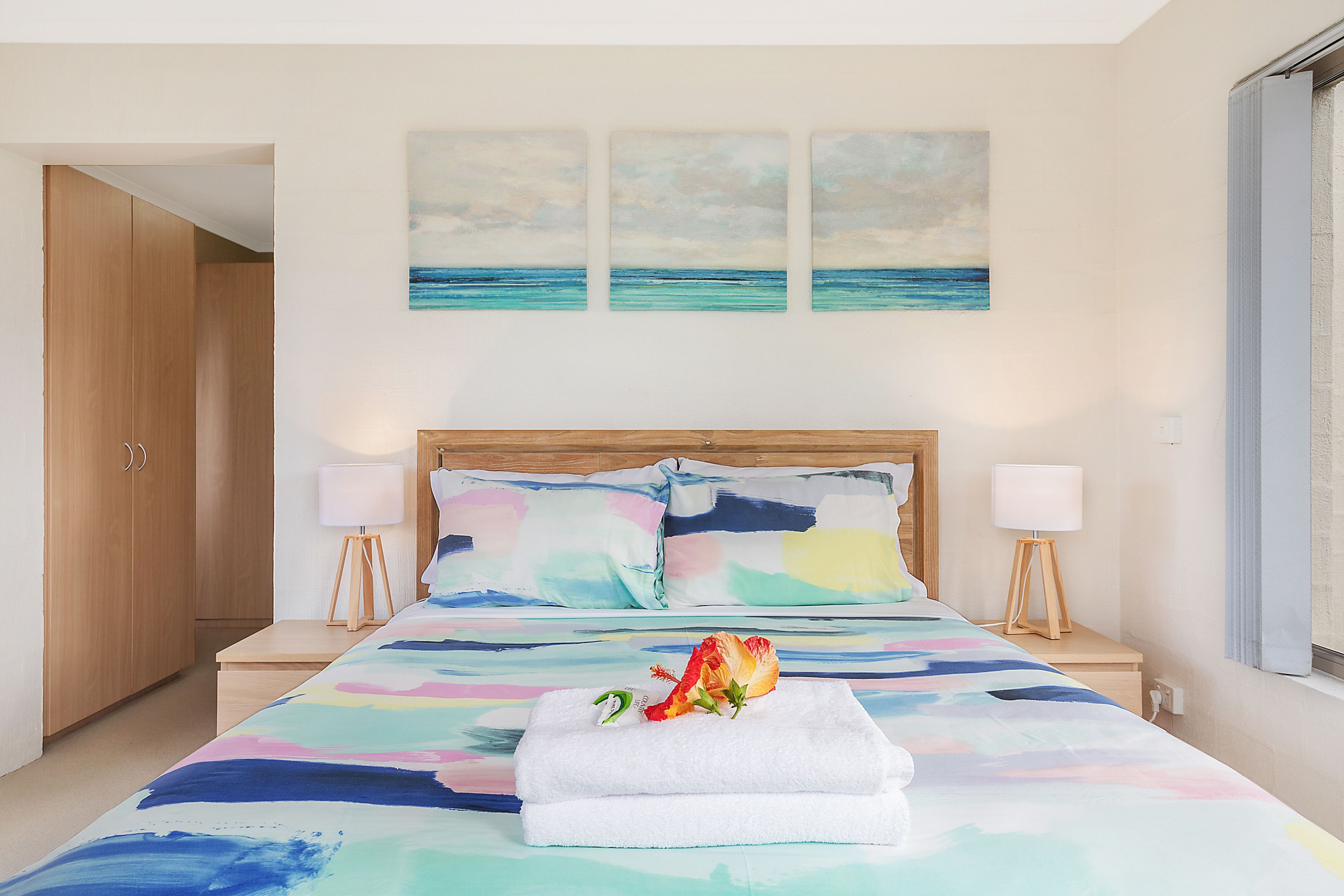 A bedroom with a bed, two bedside tables, a nightstand, and a window.