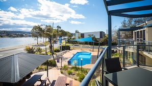 Un balcon avec vue sur une piscine, une plage et une étendue d’eau.