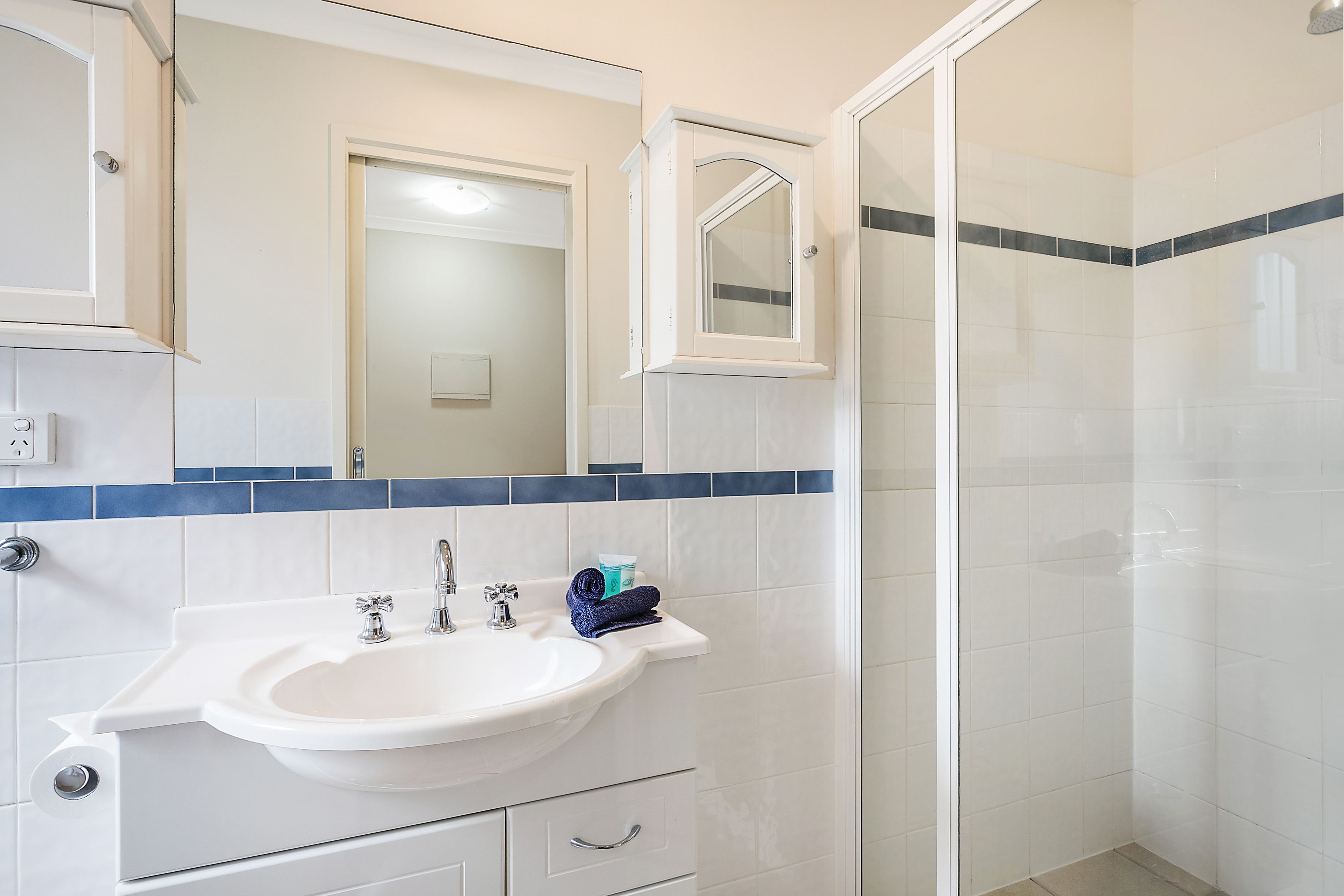 A bathroom with a sink, mirror, and shower.