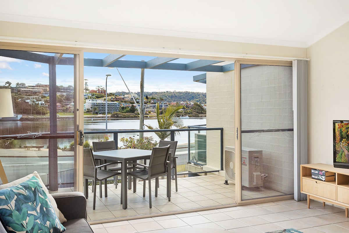 A balcony with a table and chairs, a sofa, and a TV stand.