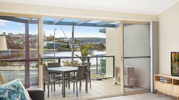 A balcony with a table and chairs, a sofa, and a TV stand.