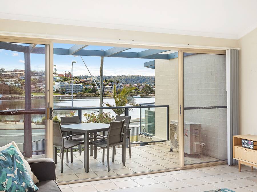 A balcony with a table and chairs, a sofa, and a TV stand.