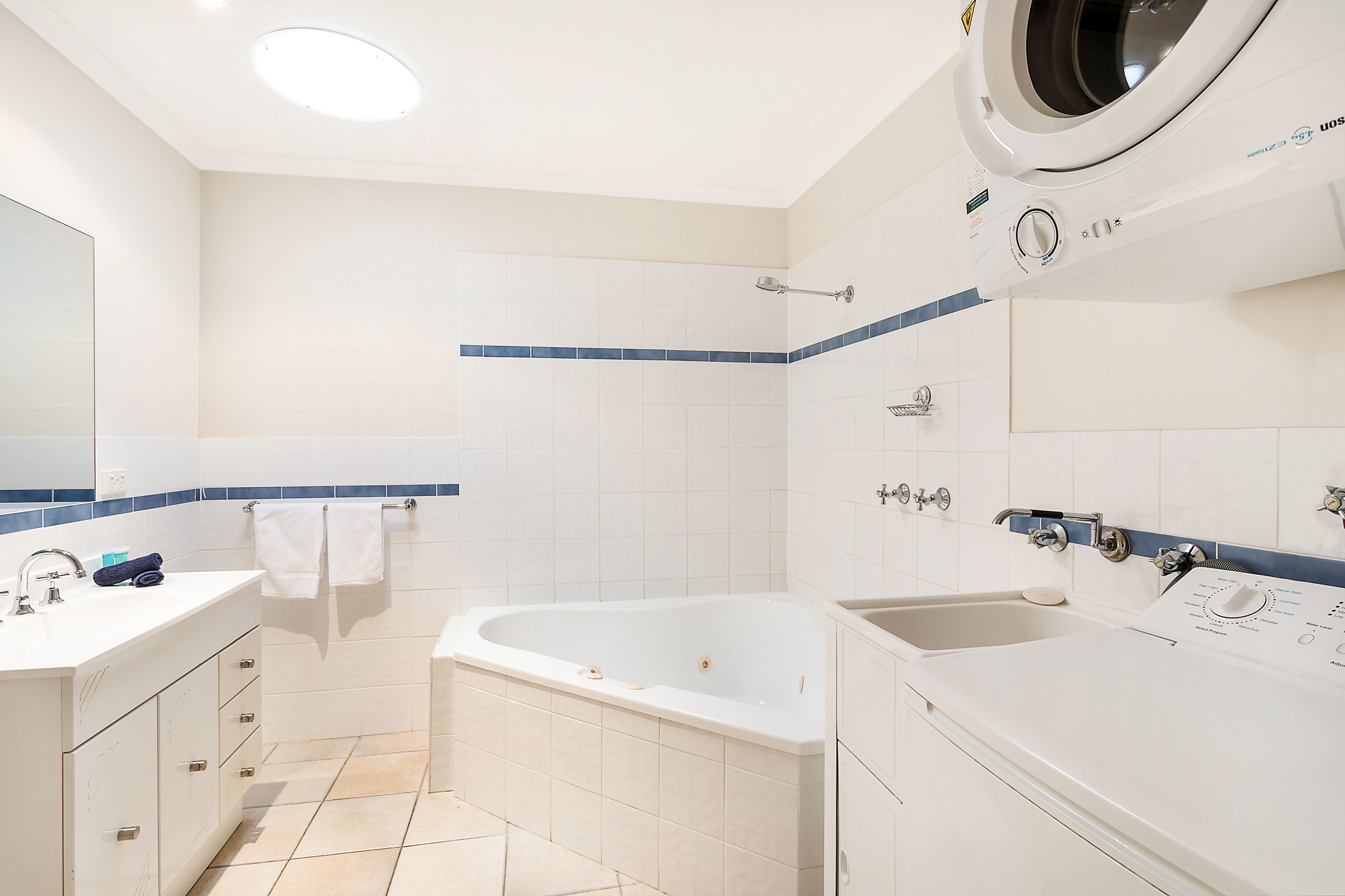 A modern bathroom with a bathtub, a sink, and a washing machine.