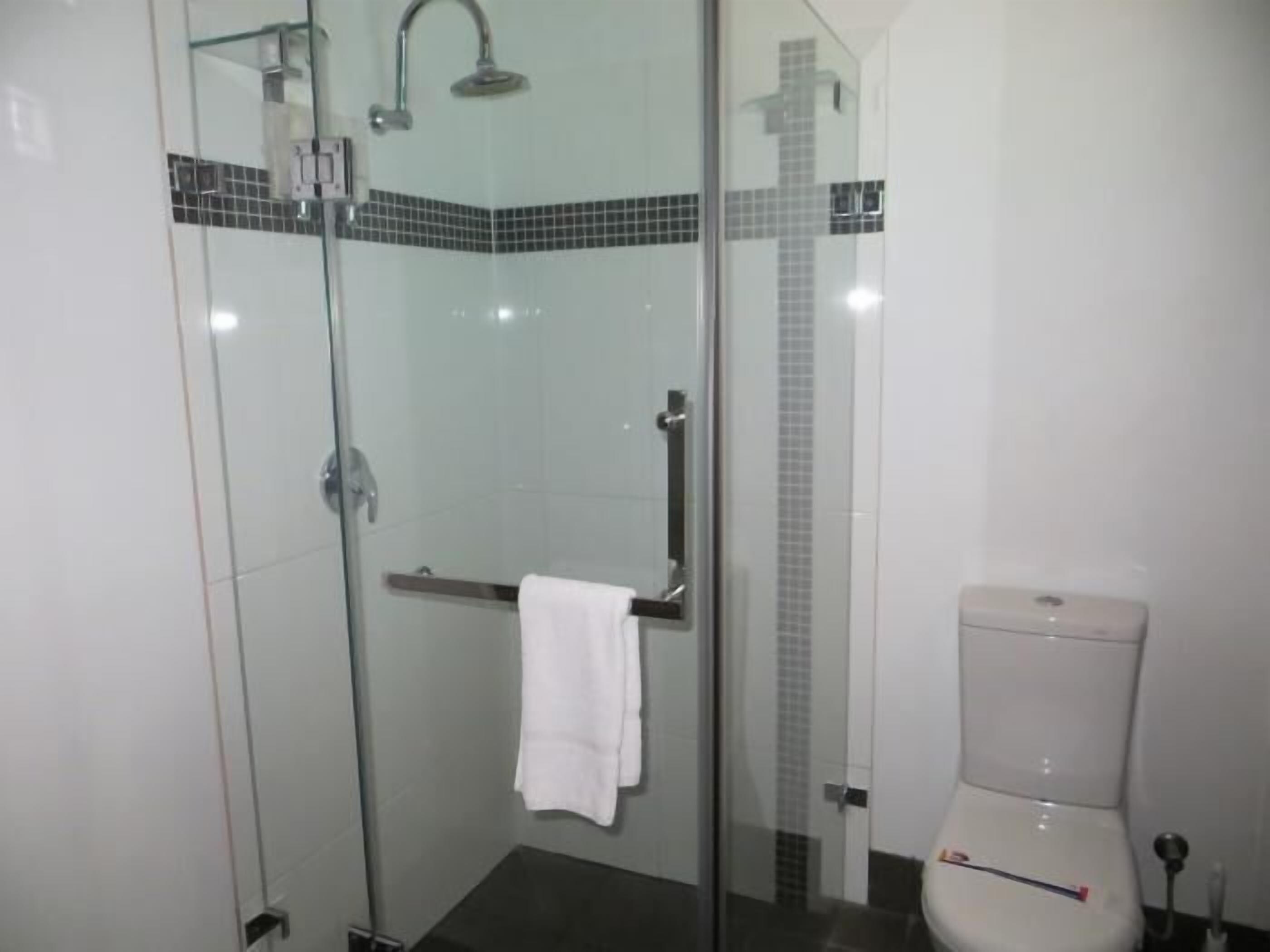 A modern bathroom with a glass-enclosed shower, a white toilet, and a towel hanging on a rack.