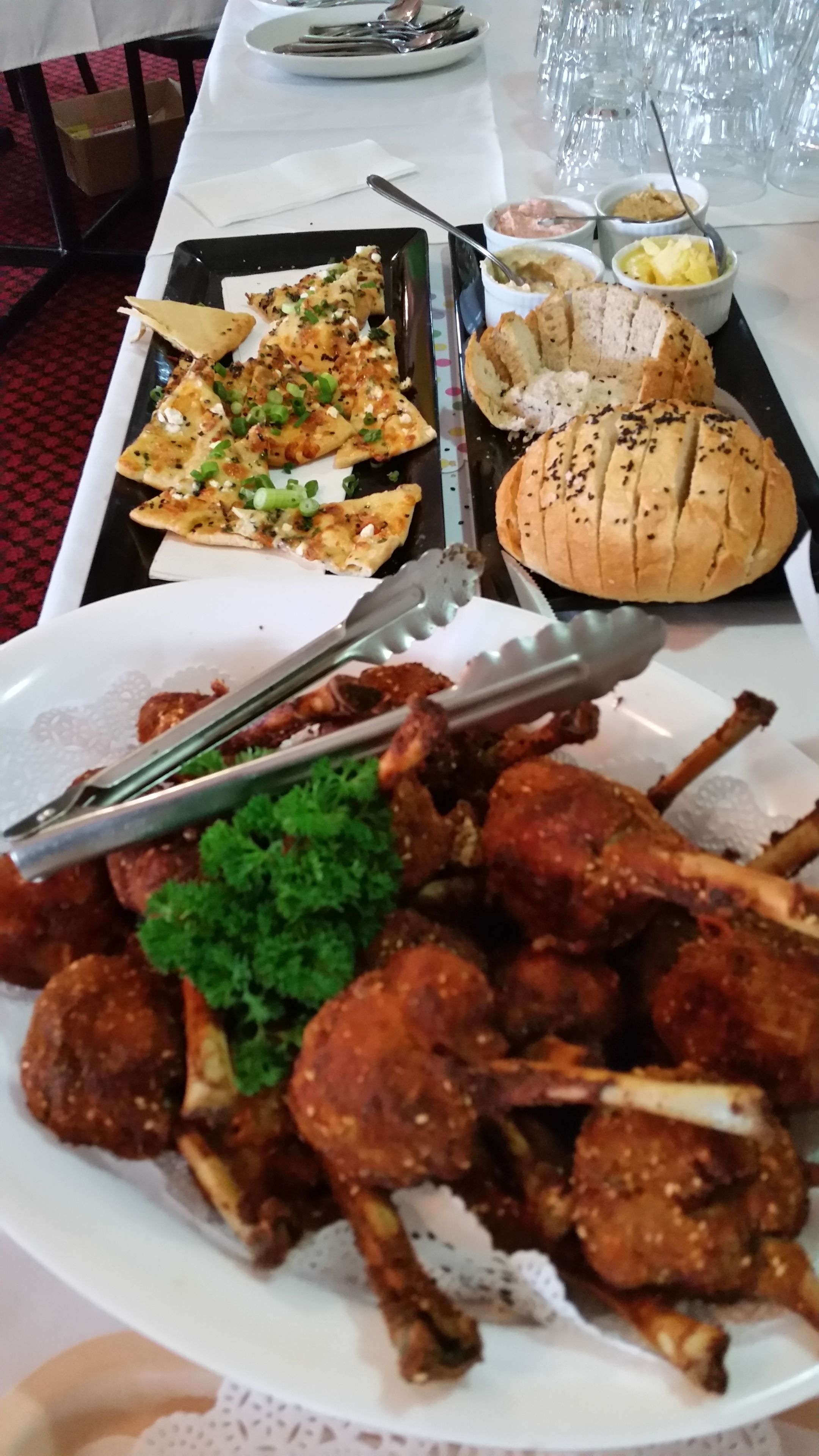 A table with various dishes including grilled chicken, a sandwich, and a side of vegetables.
