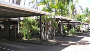 Un área de estacionamiento techada con palmeras y un edificio de ladrillo.