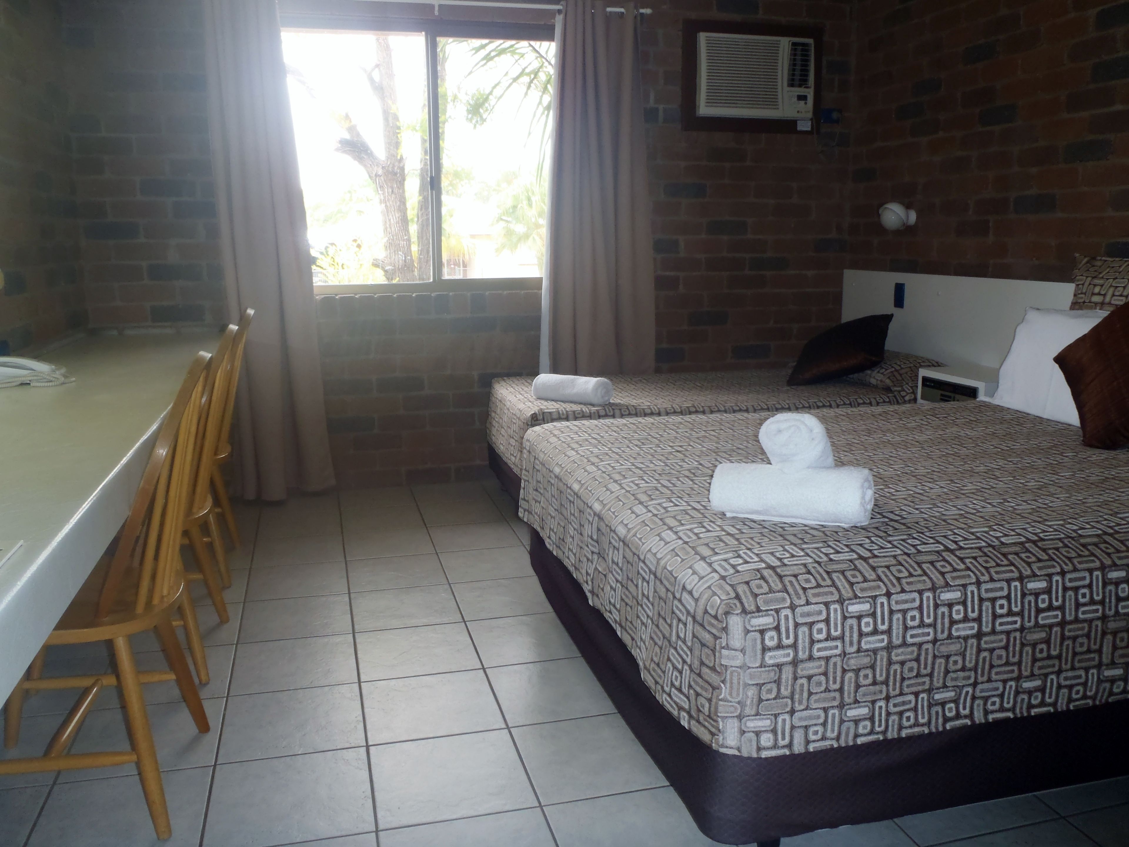 Una habitación de hotel con dos camas, un escritorio y sillas.