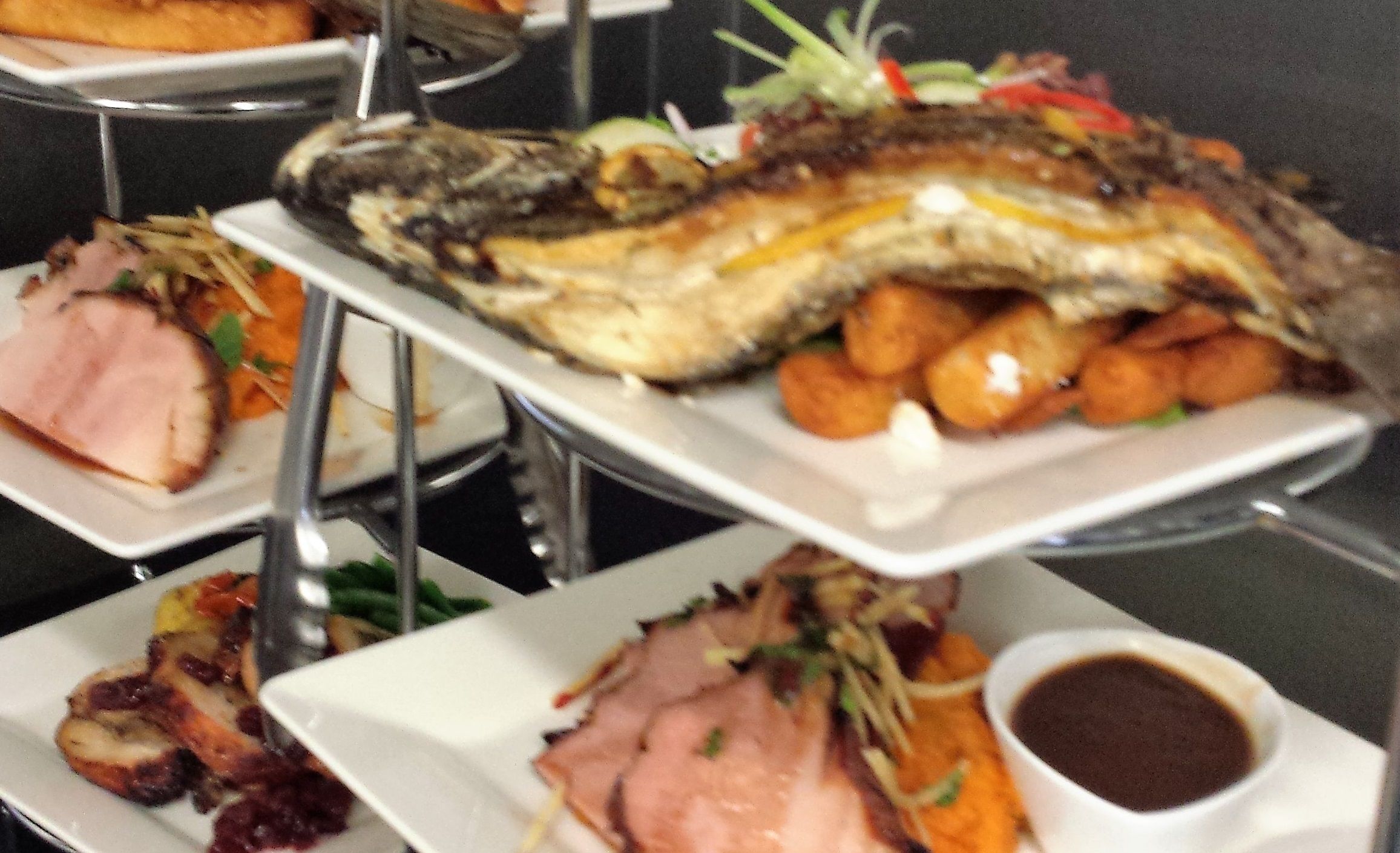 Un buffet proposant divers plats, notamment des viandes rôties, des légumes et du poisson.