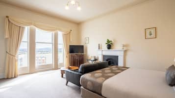 A bedroom with a large bed, a television, a fireplace, and a balcony with curtains.