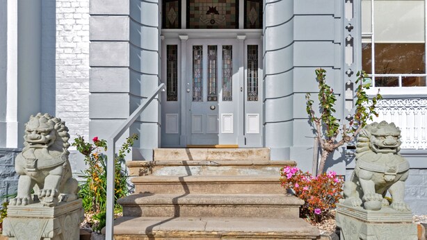 A building with a white facade, a set of stone steps leading to a door with stained glass panels, and two stone lion statues on either side. - Waratah on York (Launceston)