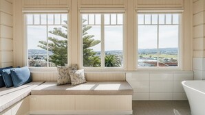 A bathroom with a bench seat, large windows, and a bathtub. - Waratah on York (Launceston)