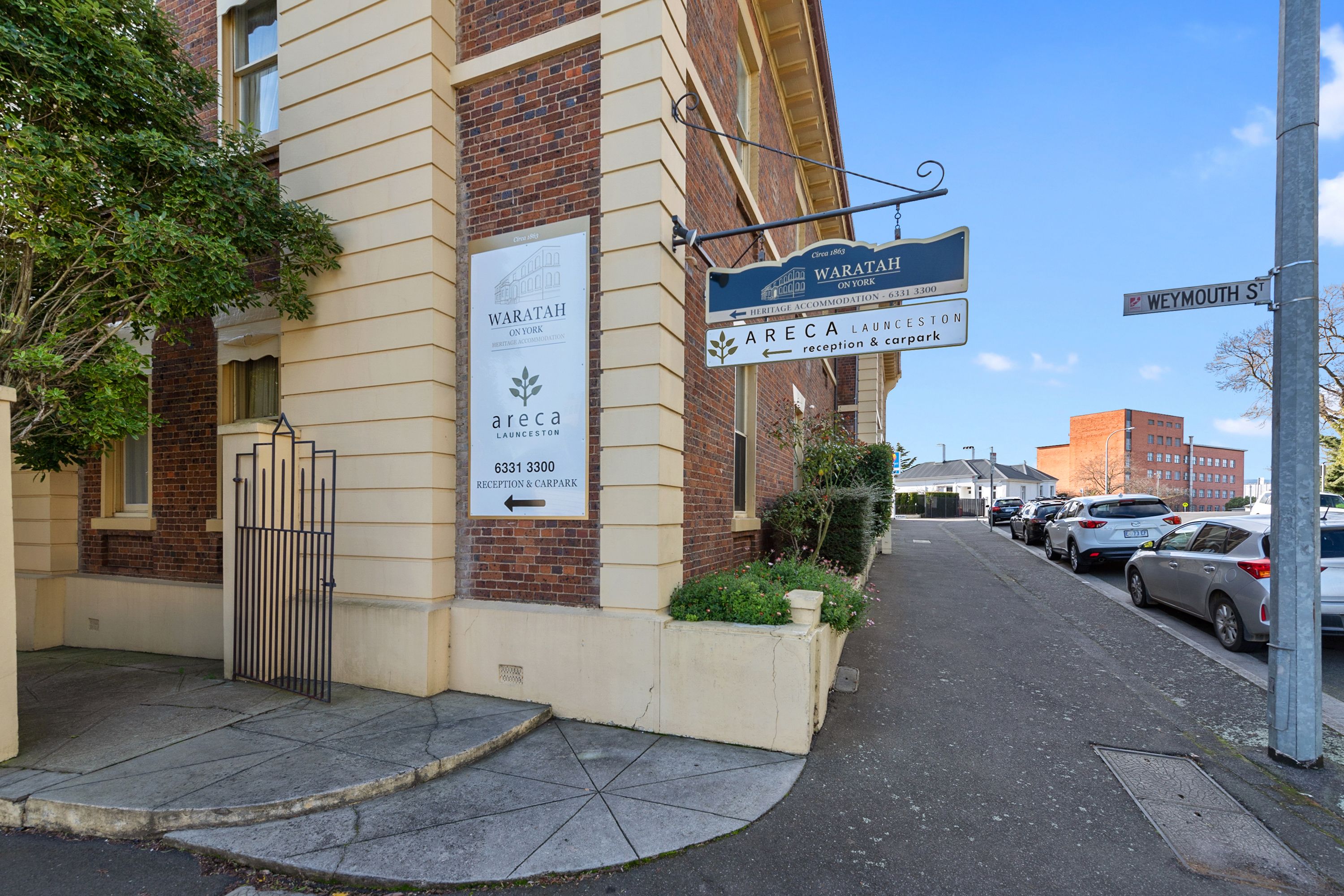 Un bâtiment portant une enseigne indiquant « Waratah on York » et « Areca Launceston », avec une réception et un parking.