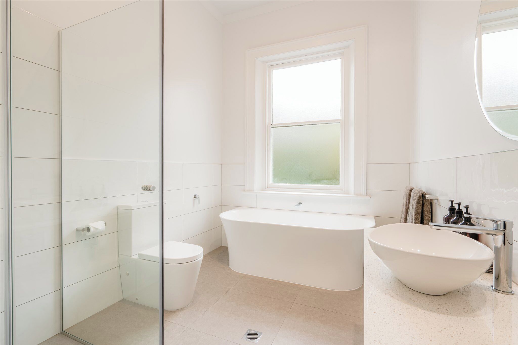 A modern bathroom with a freestanding bathtub, a toilet, and a glass shower enclosure.