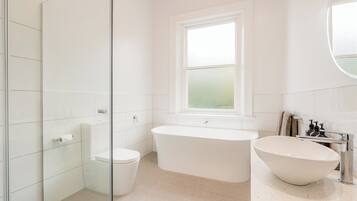 A modern bathroom with a freestanding bathtub, a toilet, and a glass shower enclosure.