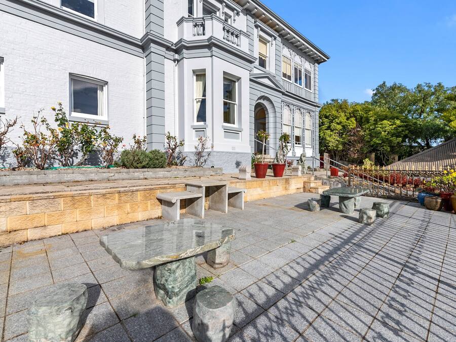 A courtyard with stone benches, a building with arched windows, and potted plants.