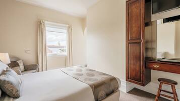 A hotel room with a bed, a desk, a chair, and a wardrobe.
